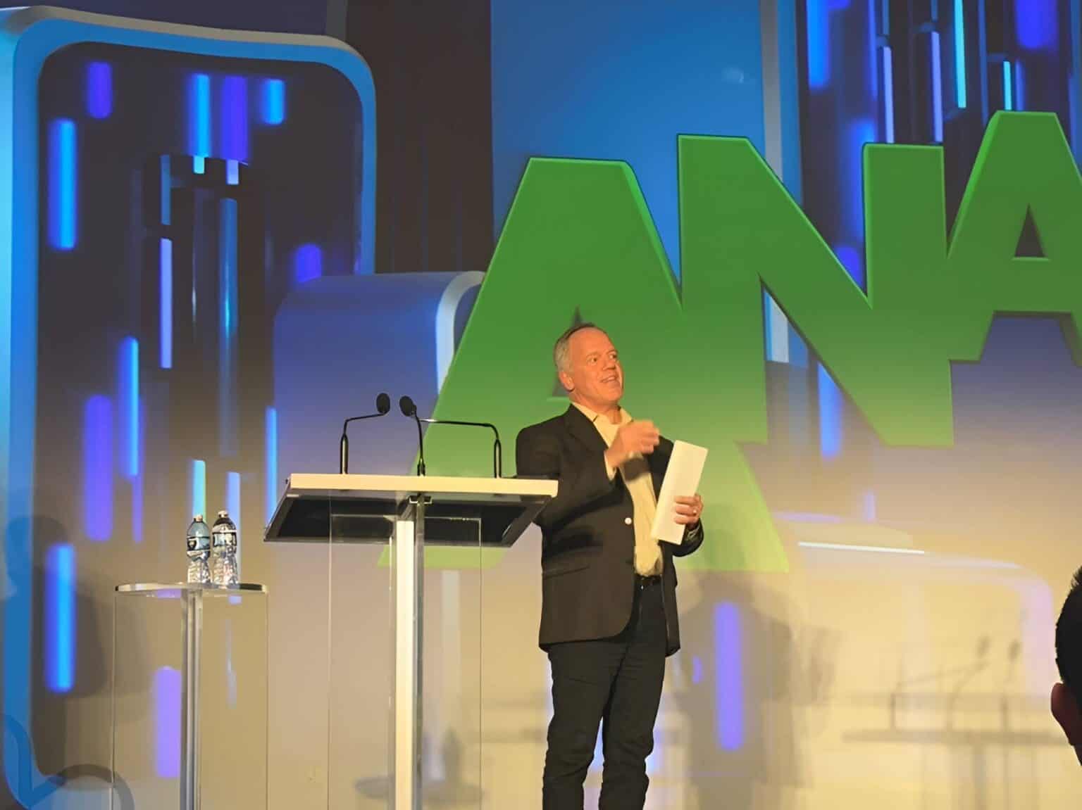 Speaker presenting at ANA landing page event with large ANA sign in background.