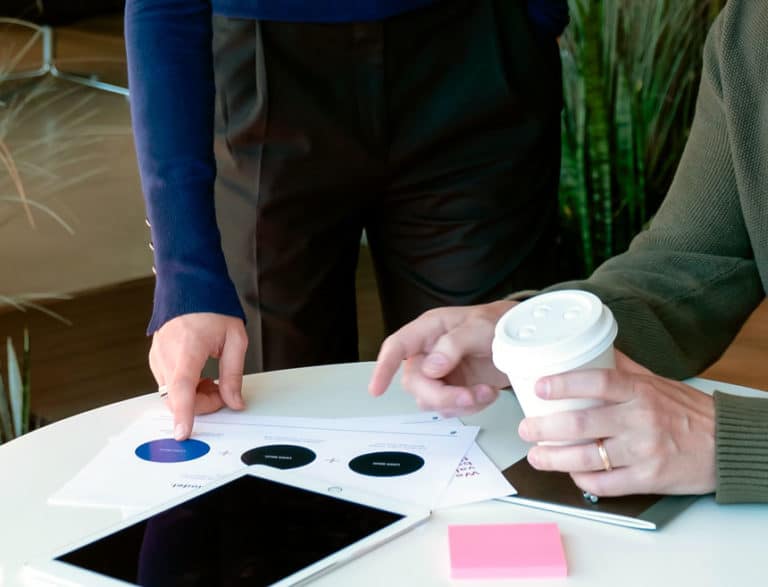 Cropped photo of two people pointing at papers on a table.